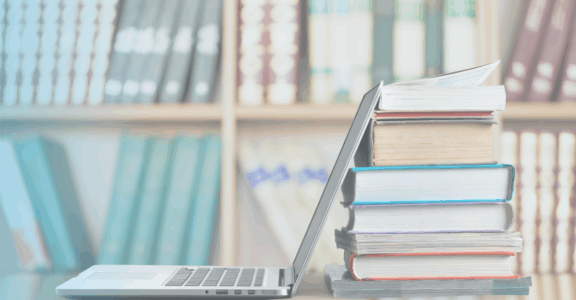 An open laptop against a stack of books