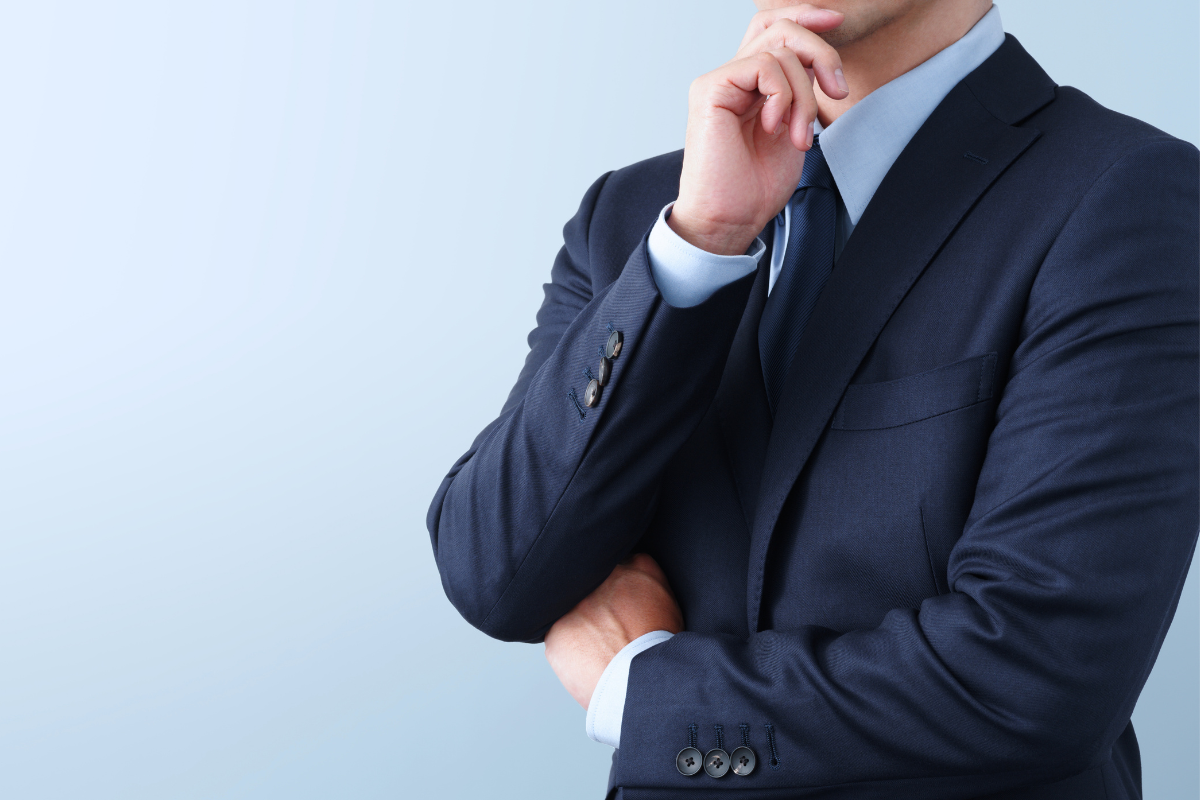 A business person in a suit thinking with their hand on their chin